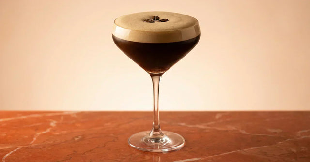 Espresso Martini auf orangenem Marmor mit drei Kaffeebohnen
